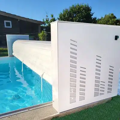 Piscine avec volet roulant automatique blanc à lattes, partiellement déployé. Structure blanche décorative avec motif égaliseur audio.
